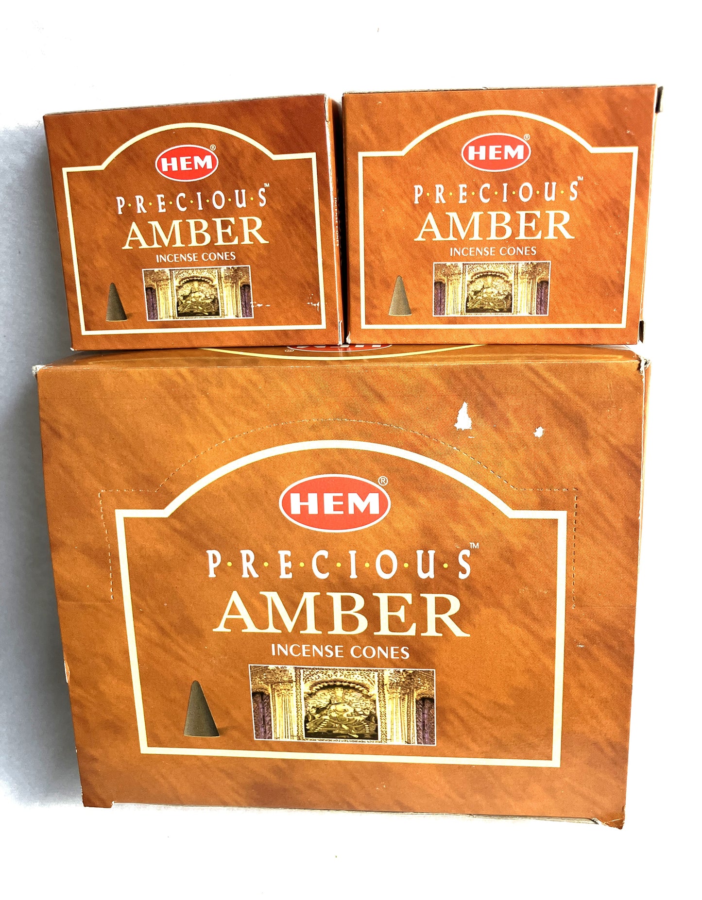 Master carton and two boxes of HEM Precious Amber incense cones shown on a white background