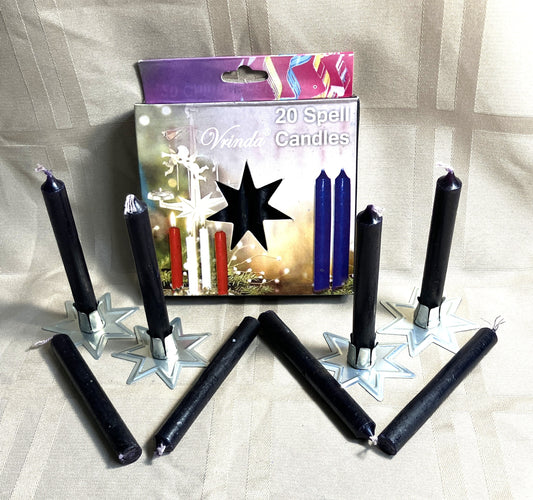 Black spell candles with packaging on a striped fabric background