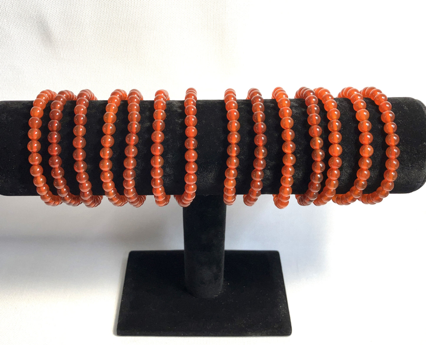 Carnelian Beaded Stretch Bracelets on a black stand against a white background