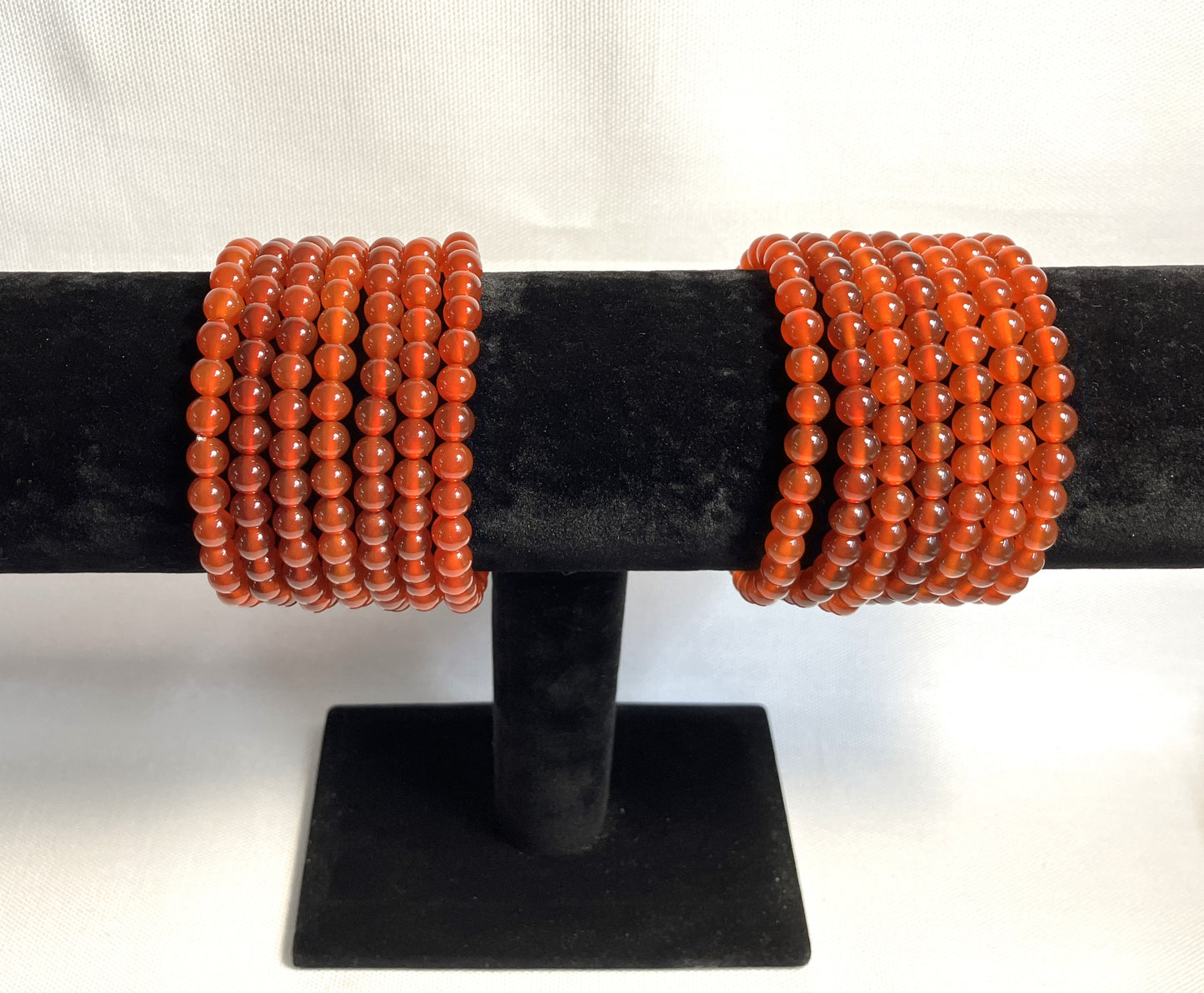 Carnelian Beaded Stretch Bracelets on a black stand shown on a white background