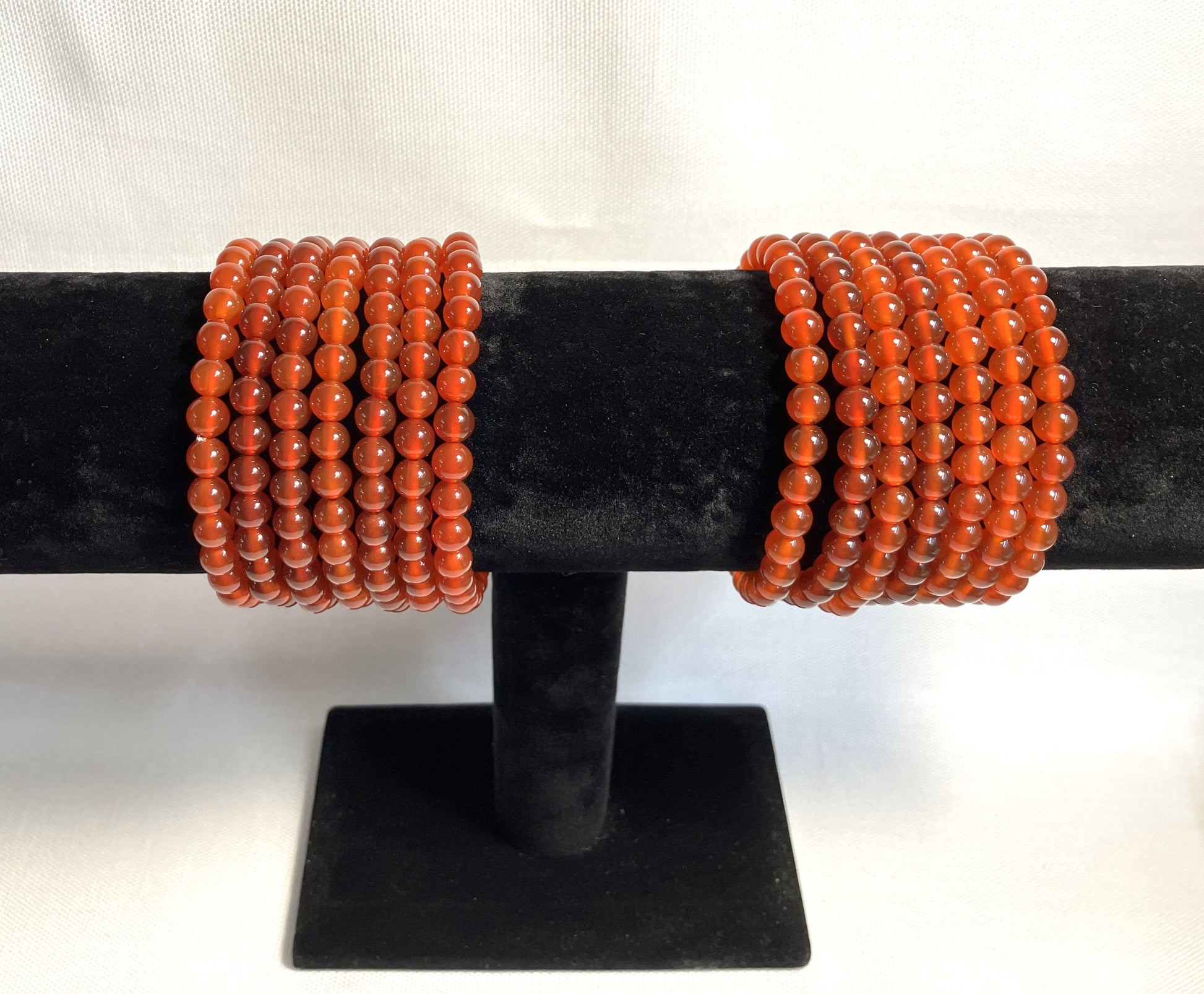 Carnelian Beaded Stretch Bracelets on a black stand shown on a white background