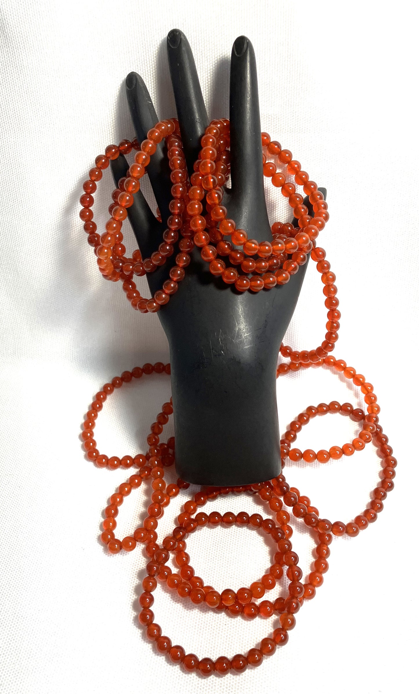 Carnelian Beaded Stretch Bracelets on a black mannequin hand against a white background