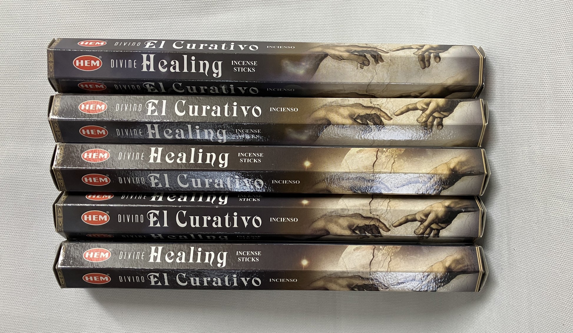 Stack of 'El Curativo' healing incense boxes on a light gray background