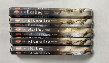 Stack of 'El Curativo' healing incense boxes on a light gray background