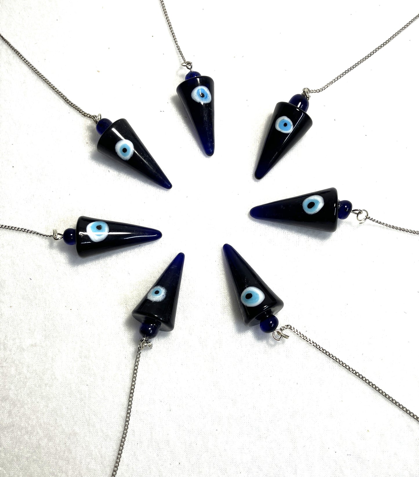 Cobalt Blue Evil Eye Pendulums with light blue eyes on white iris against a white background arranged in a circle