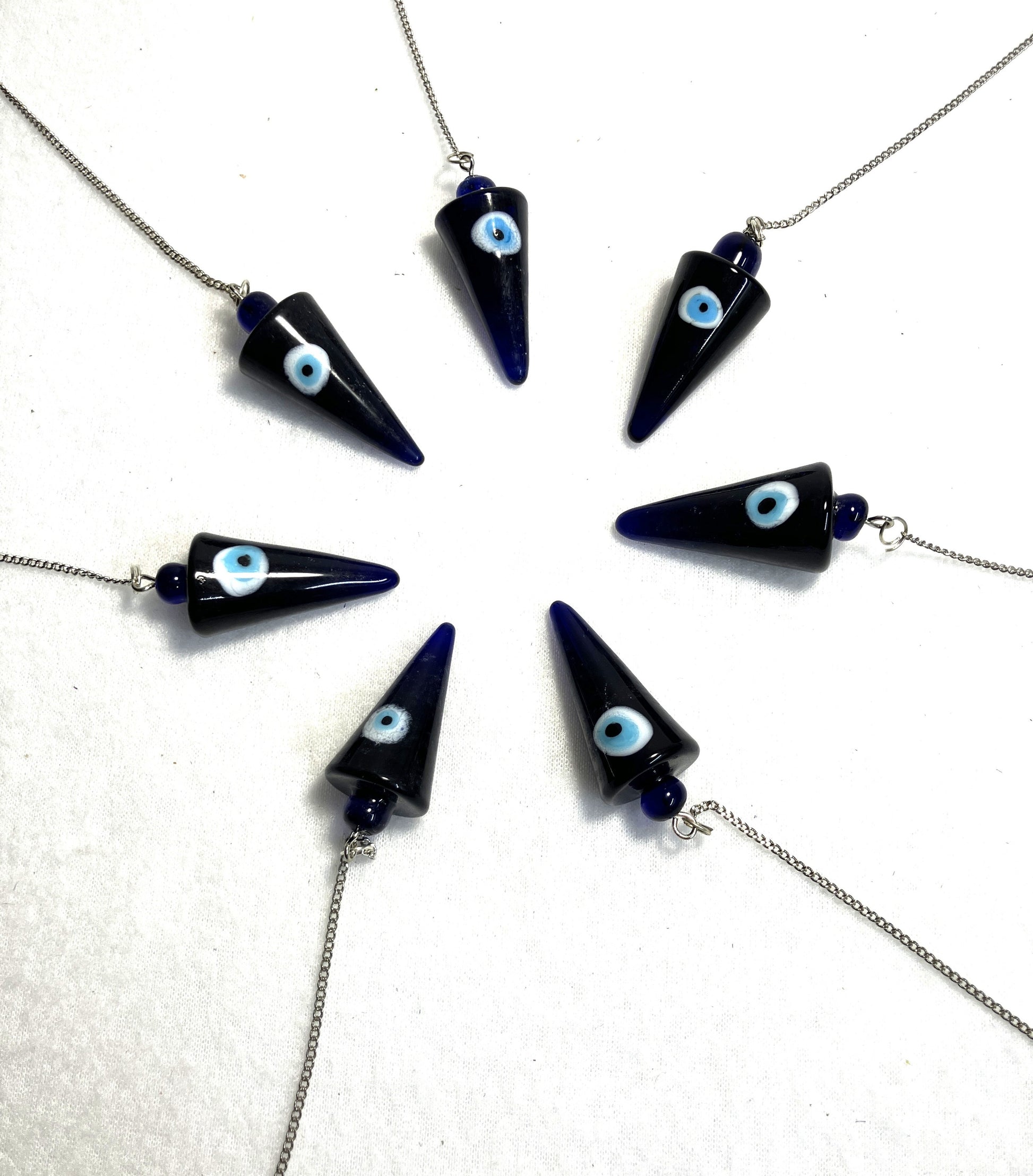 Cobalt Blue Evil Eye Pendulums with light blue eyes on white iris against a white background arranged in a circle