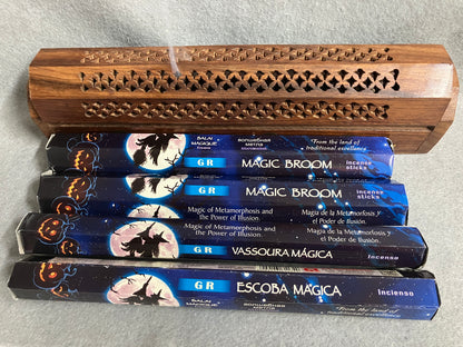 Four boxes of GR Magic Broom incense sticks if front of a decorative incense burner on a light gray background
