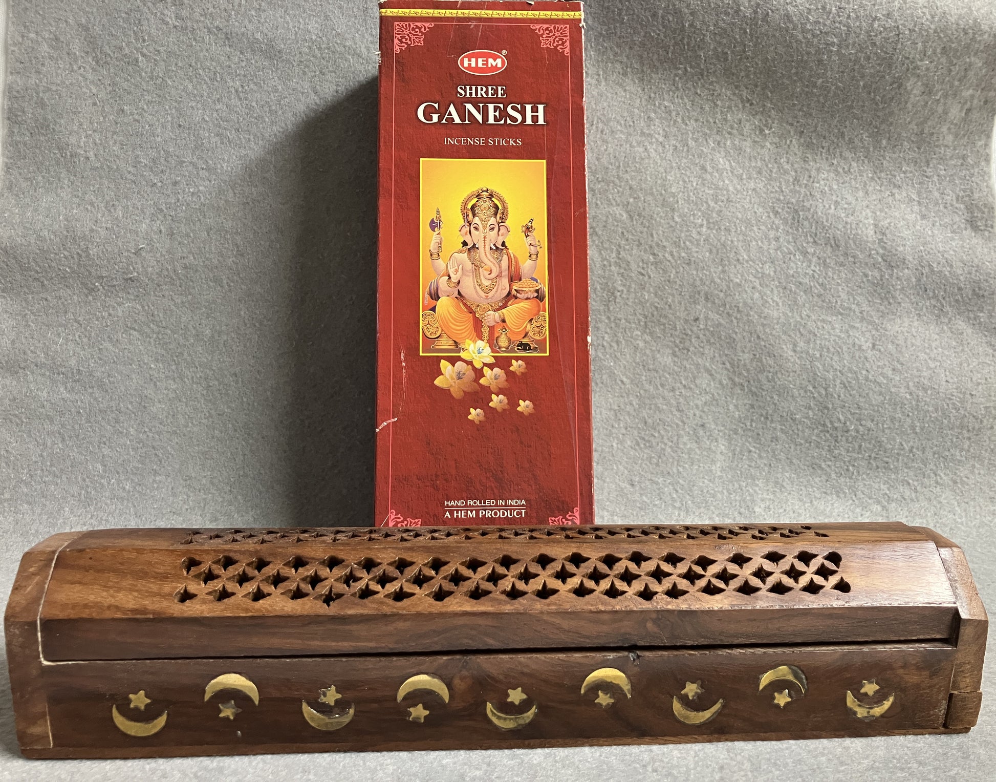 Box of Hem Shree Ganesh incense sticks shown with a wooden incense burner on a gray background