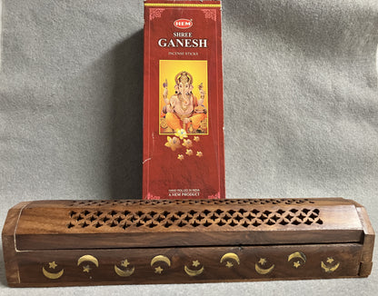 Box of Hem Shree Ganesh incense sticks shown with a wooden incense burner on a gray background