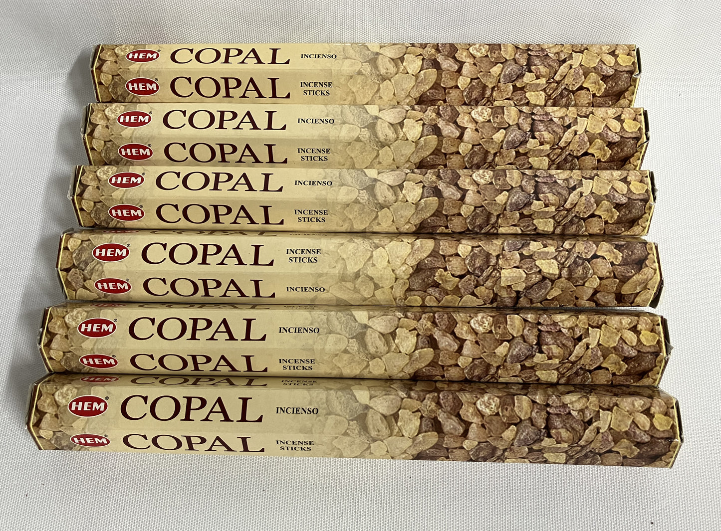 Six packages of HEM Copal incense sticks on a light gray background