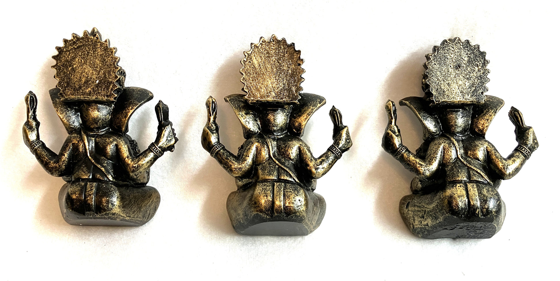Group of three Lord Ganesha statues showing back side displayed on a white background