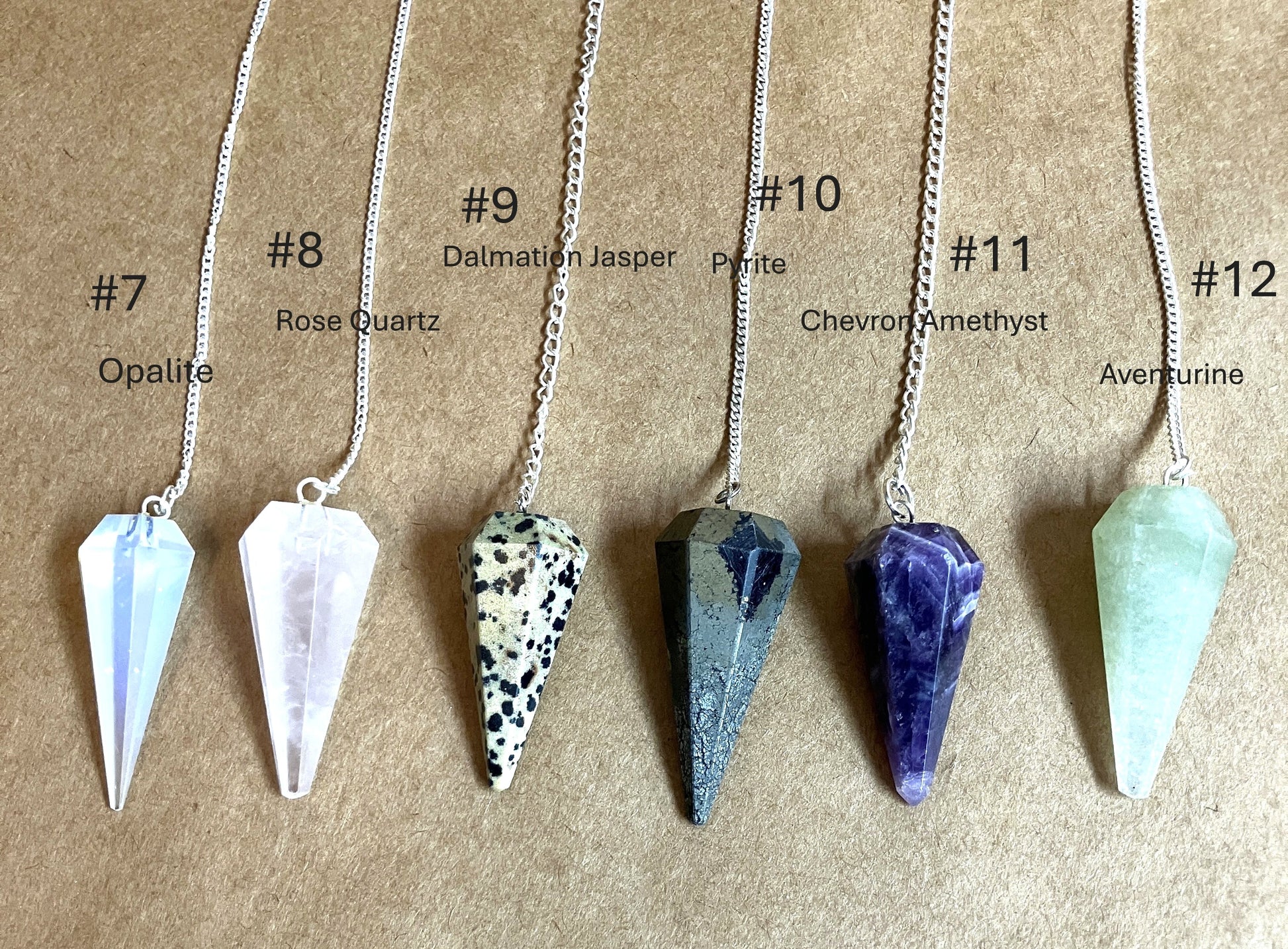 Six crystal pendulums with labels indicating the type of crystal shown on a brown background