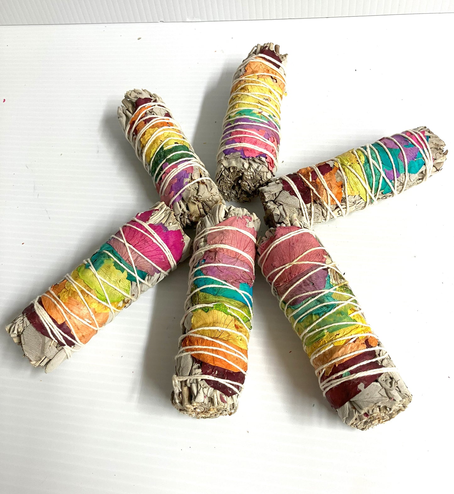 Colorful wrapped White Sage smudge sticks shown on a white background