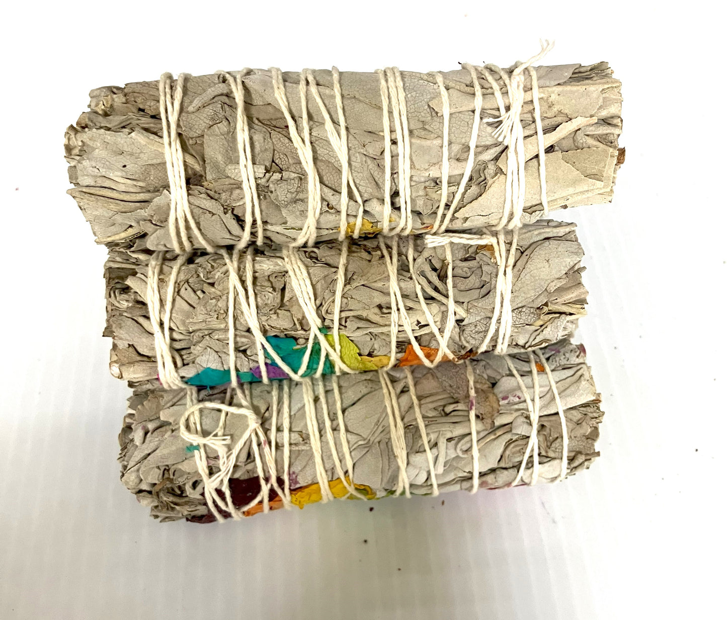 Three bundles of White Sage smudge sticks tied with white string shown on a white background