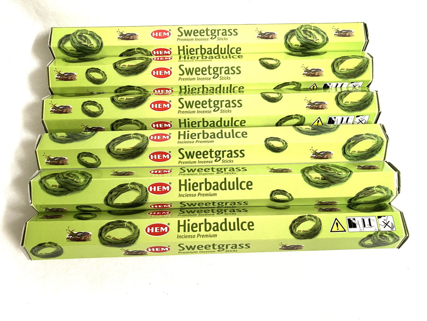 Multiple boxes of HEM Sweetgrass Hierbadulce incense on a white background