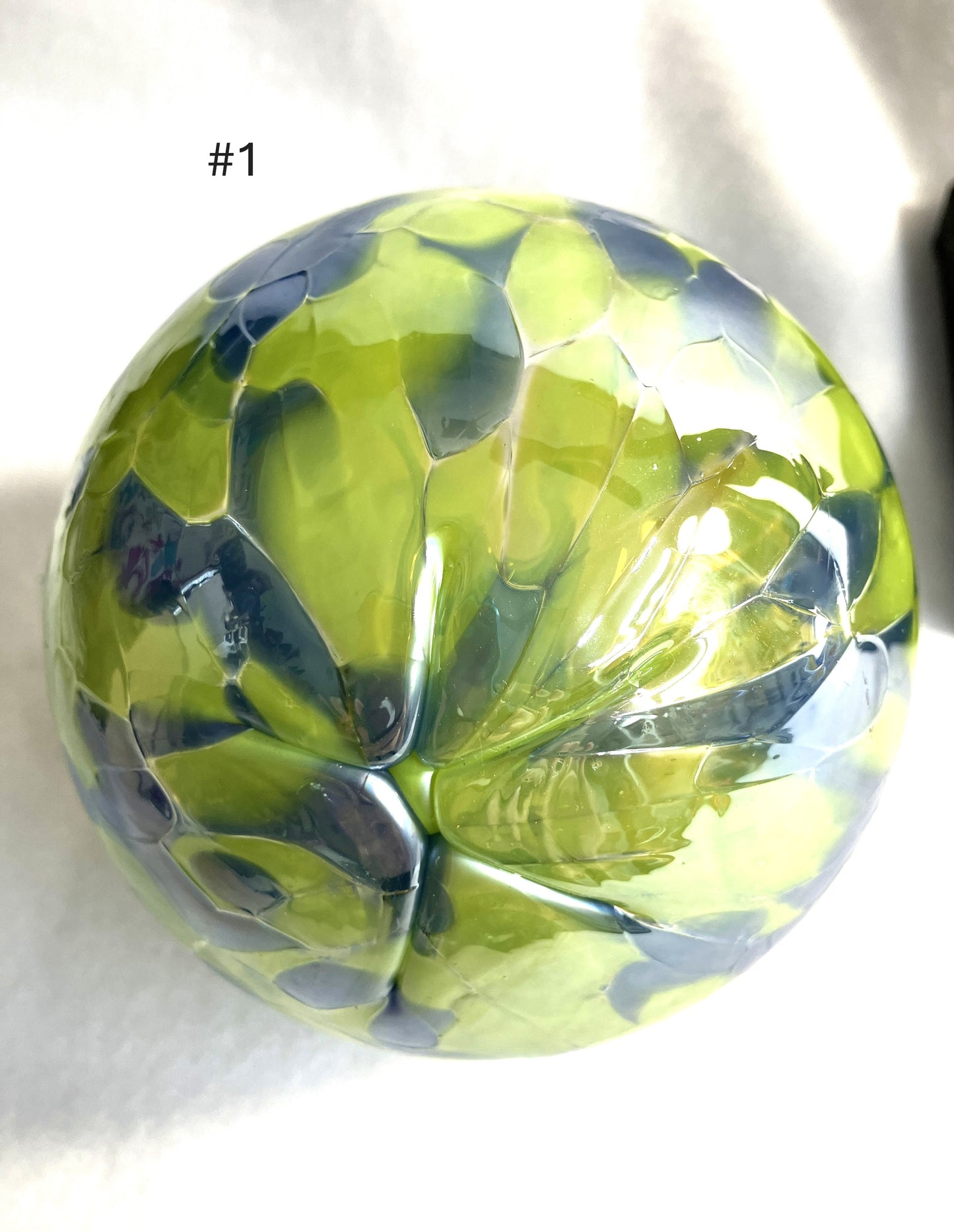 Green and blue faceted Blown Glass Witch Ball on a white background