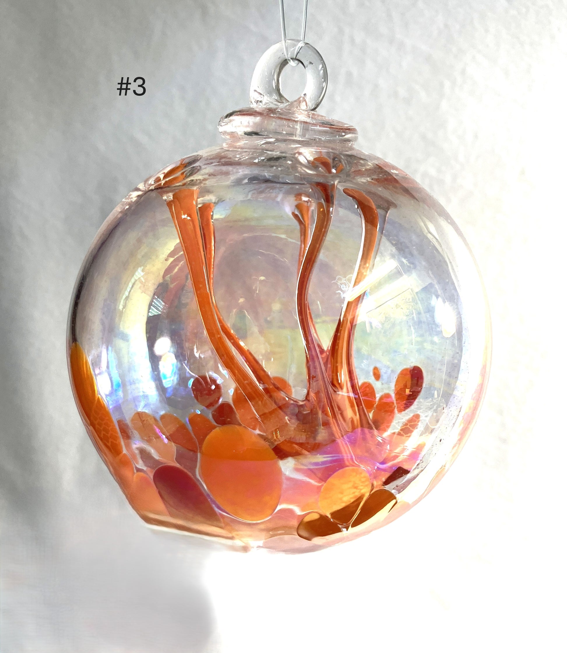 Blown Glass Witch Ball with orange and red abstract design on a white background