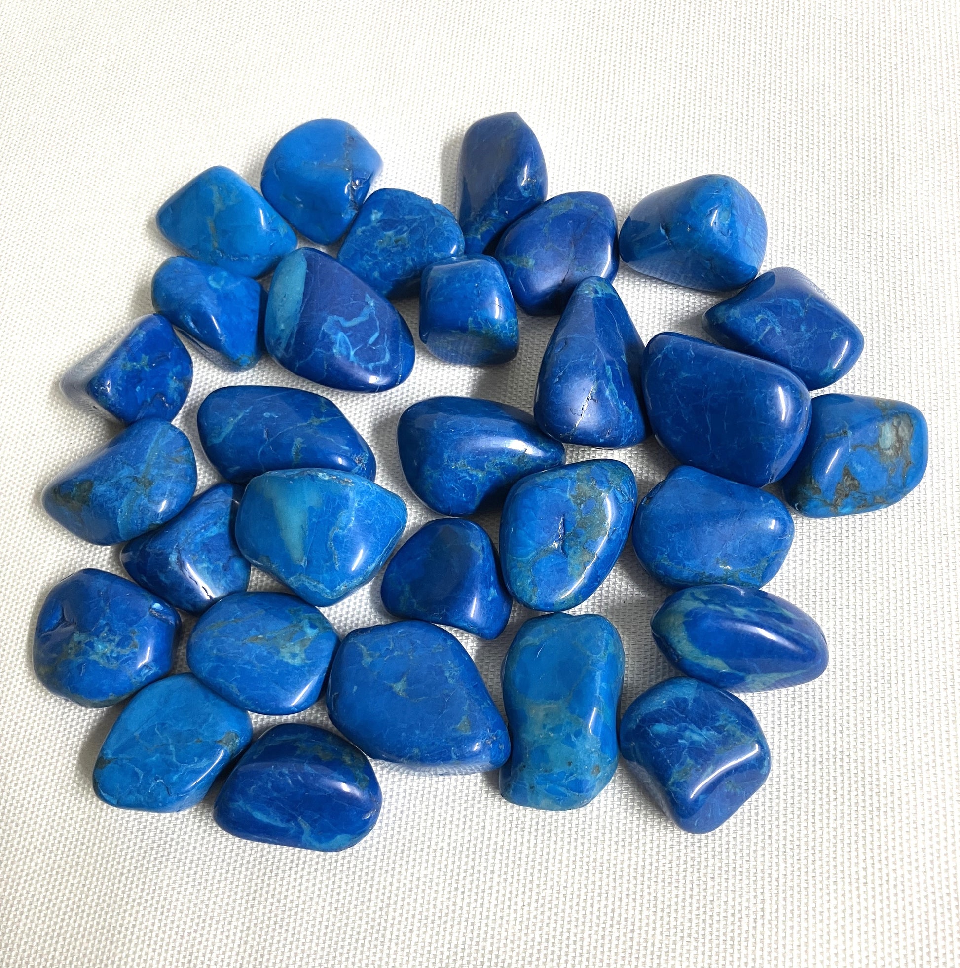Back view Dyed Blue Howlite Crystals on a white fabric background