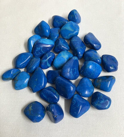 Groupe of Dyed Blue Howlite Crystals showing the variations of color displayed  on a white fabric background