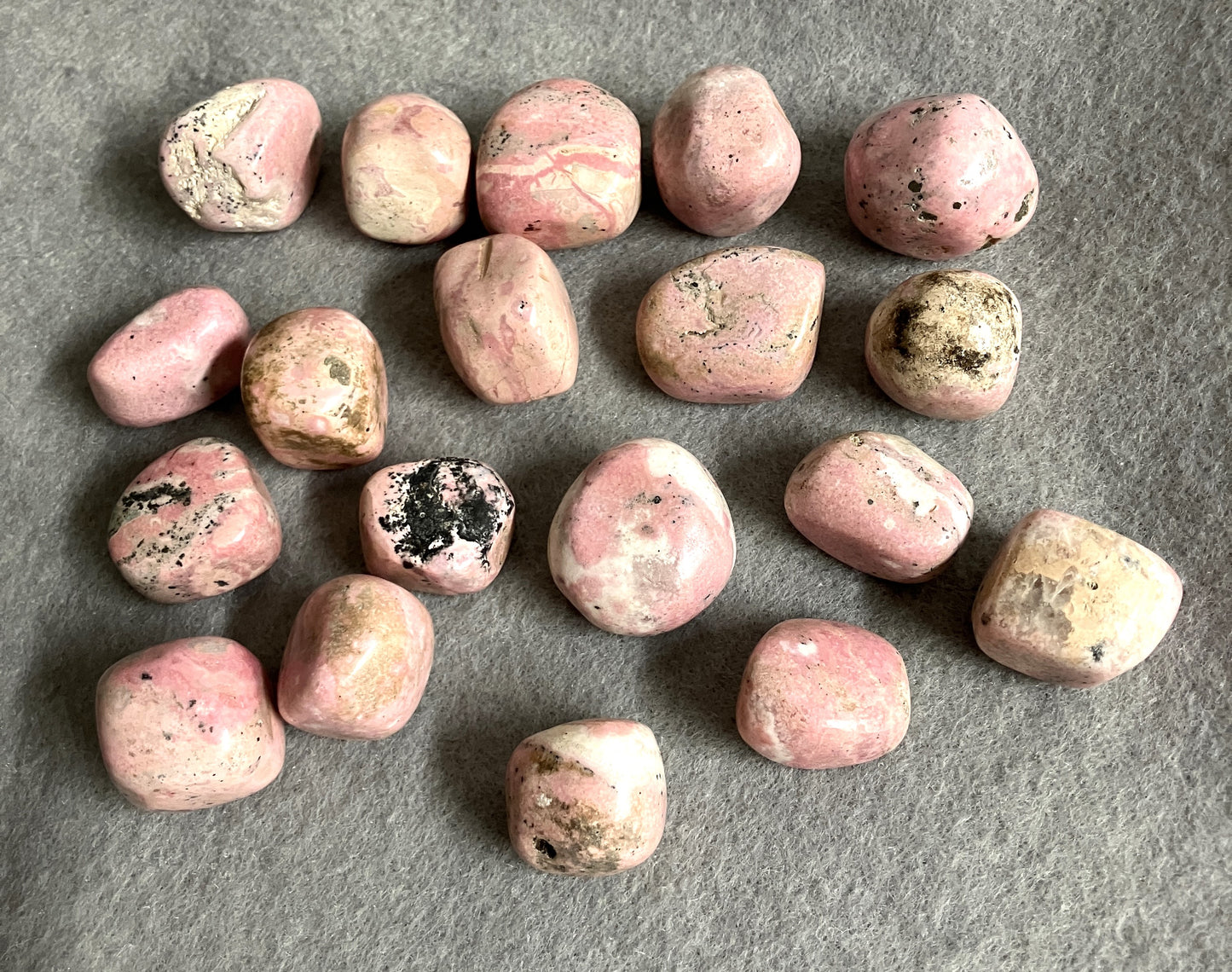 Assorted Rhodochrosite Crystals on a gray surface