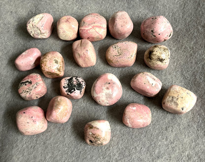 Assorted Rhodochrosite Crystals on a gray surface