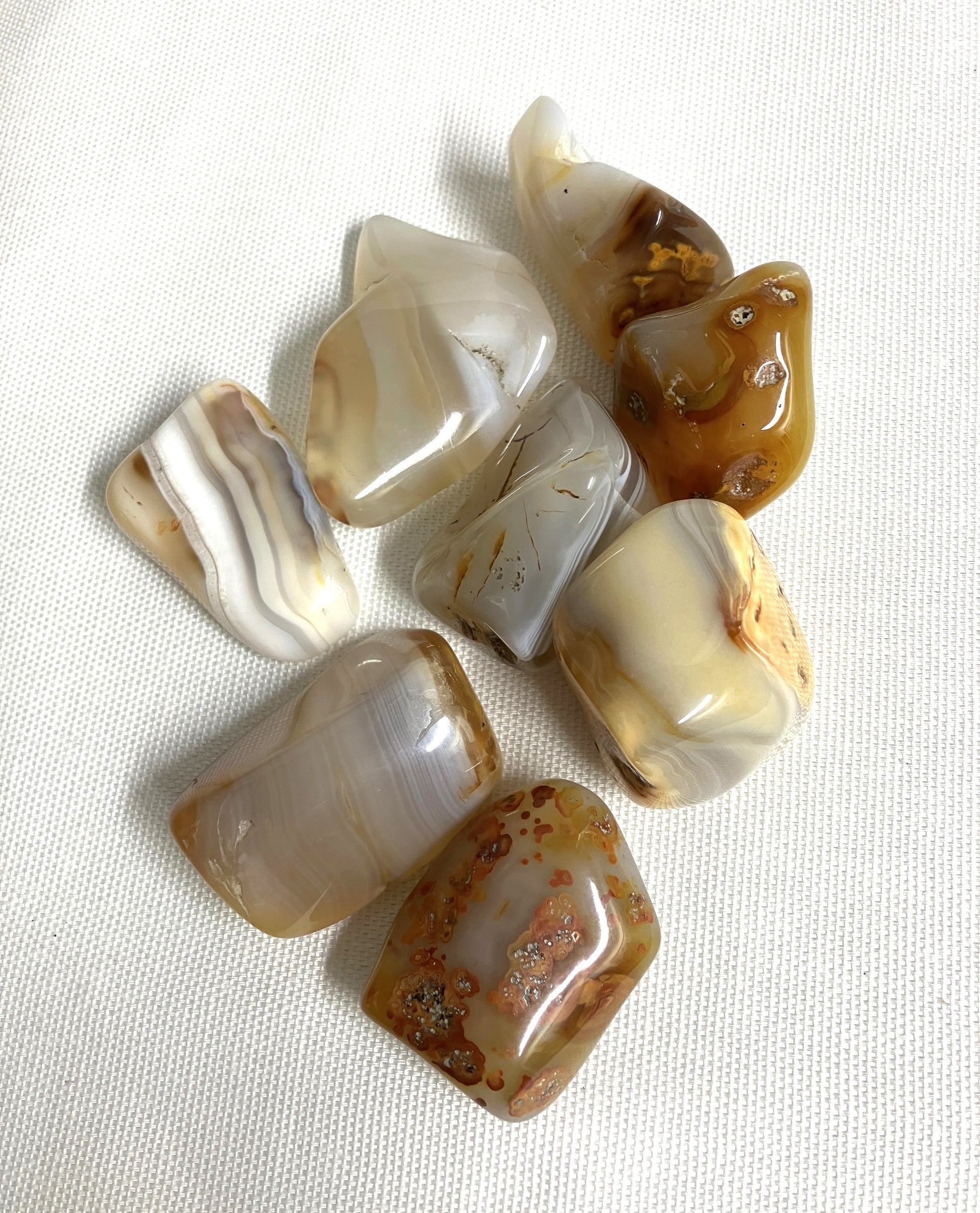 Tumbled Grey Banded Agate Crystals on a white fabric background