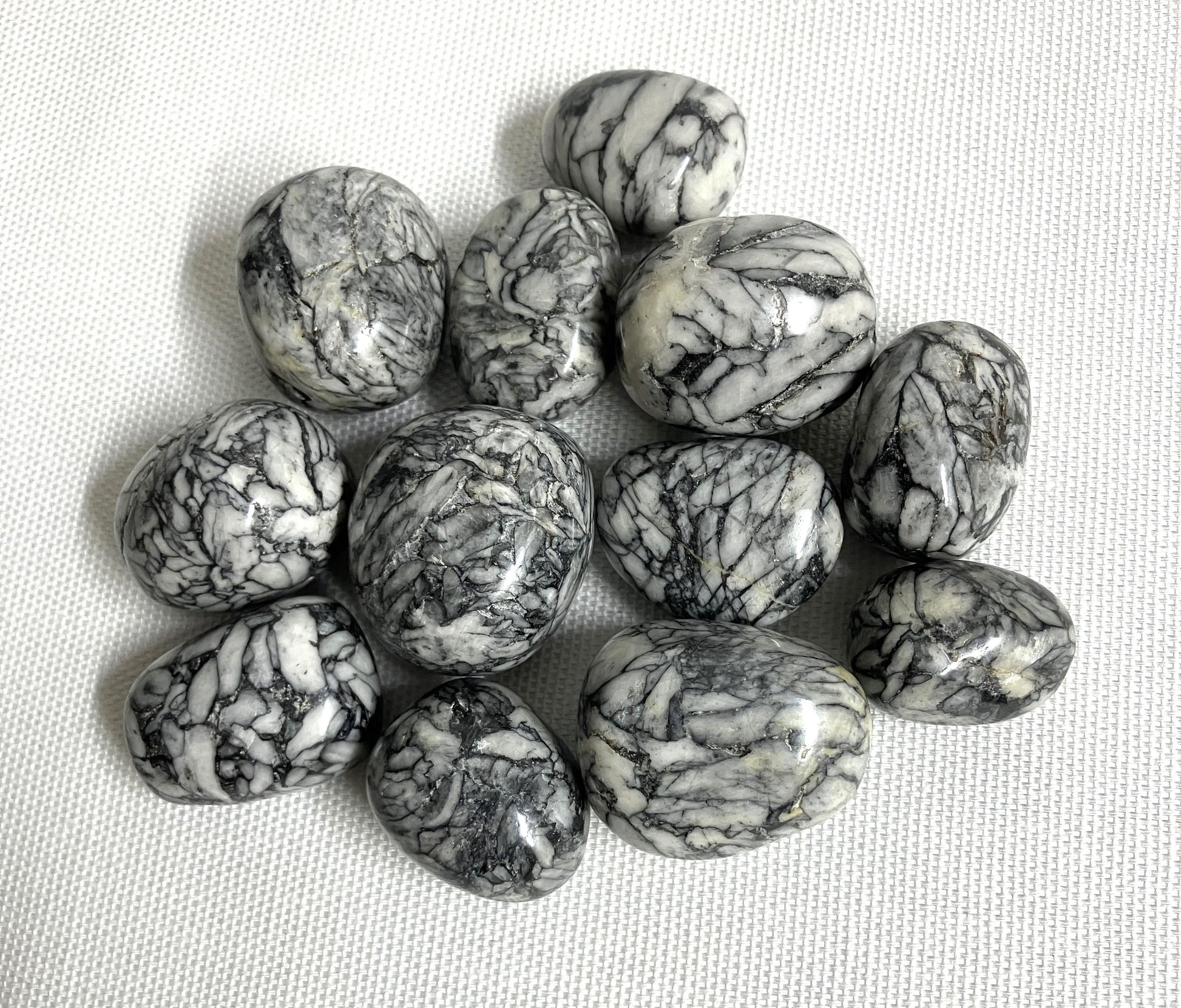 Tumbled Pinolith Jasper Crystals shown on a textured surface