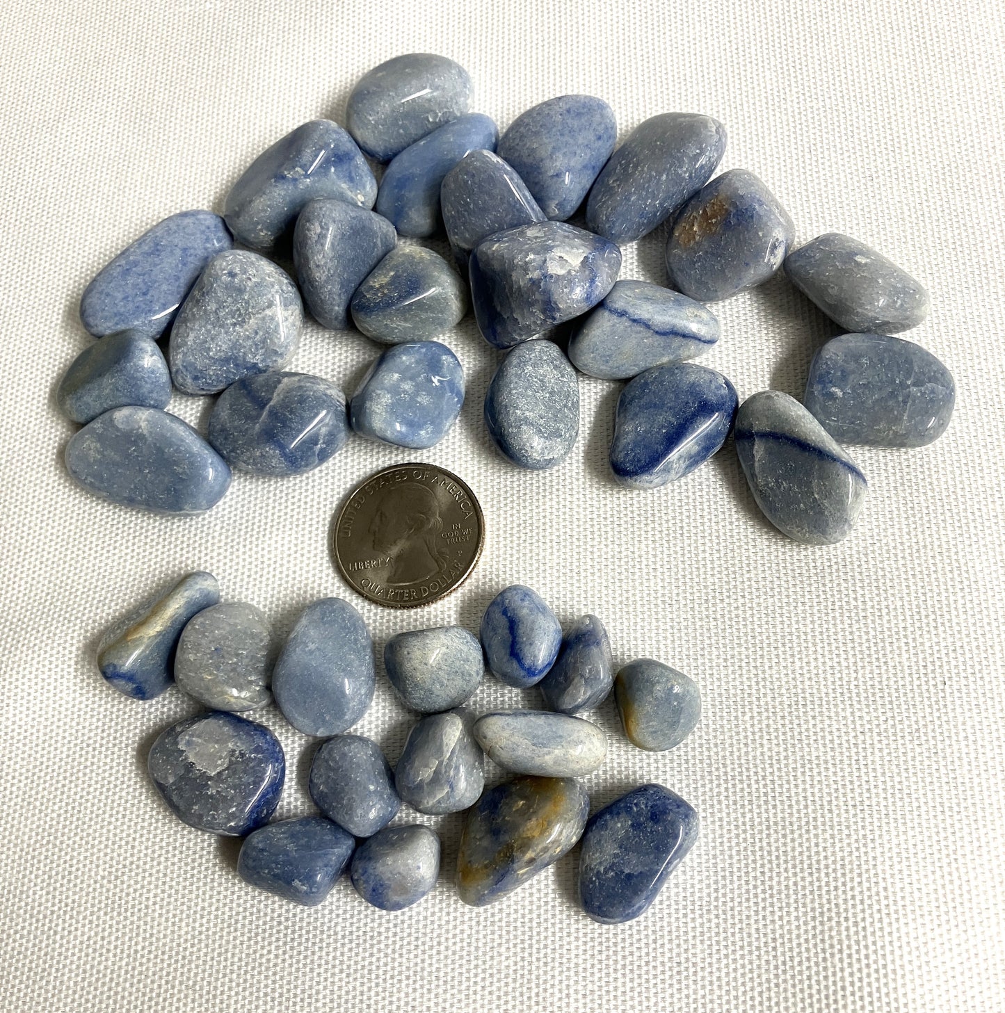 Blue Quartz Crystals on a white background with a quarter for scale