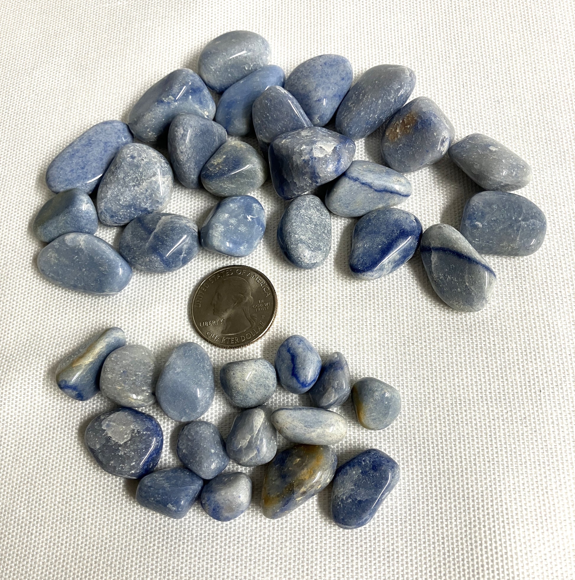 Blue Quartz Crystals on a white background with a quarter for scale