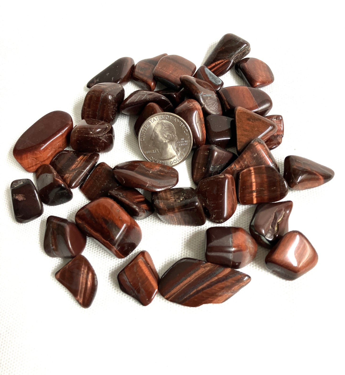 Red Tiger Eye crystals shown with a coin for size comparison.