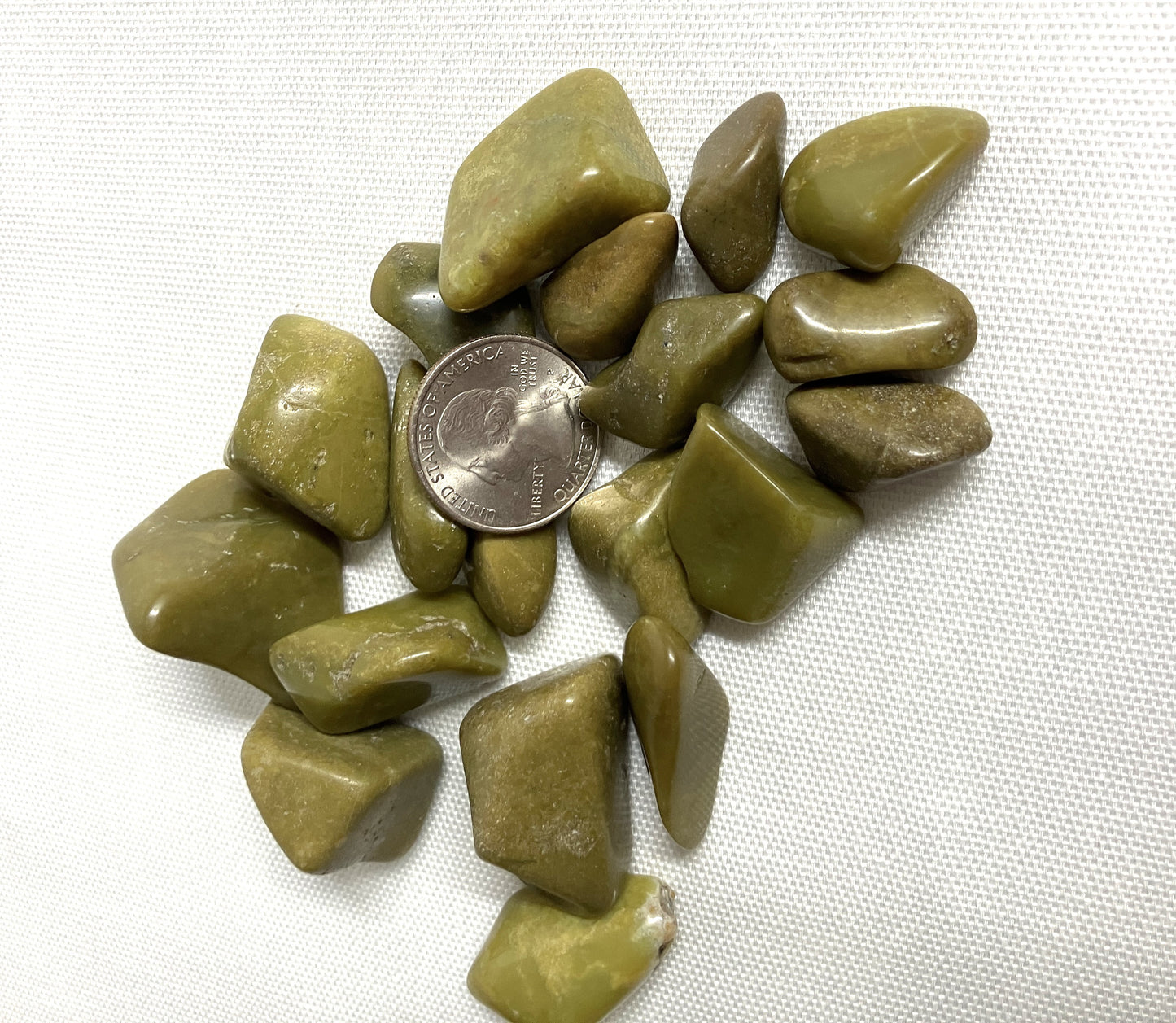 Bottom side of Green Opal Crystals on a white background with a quarter for scale