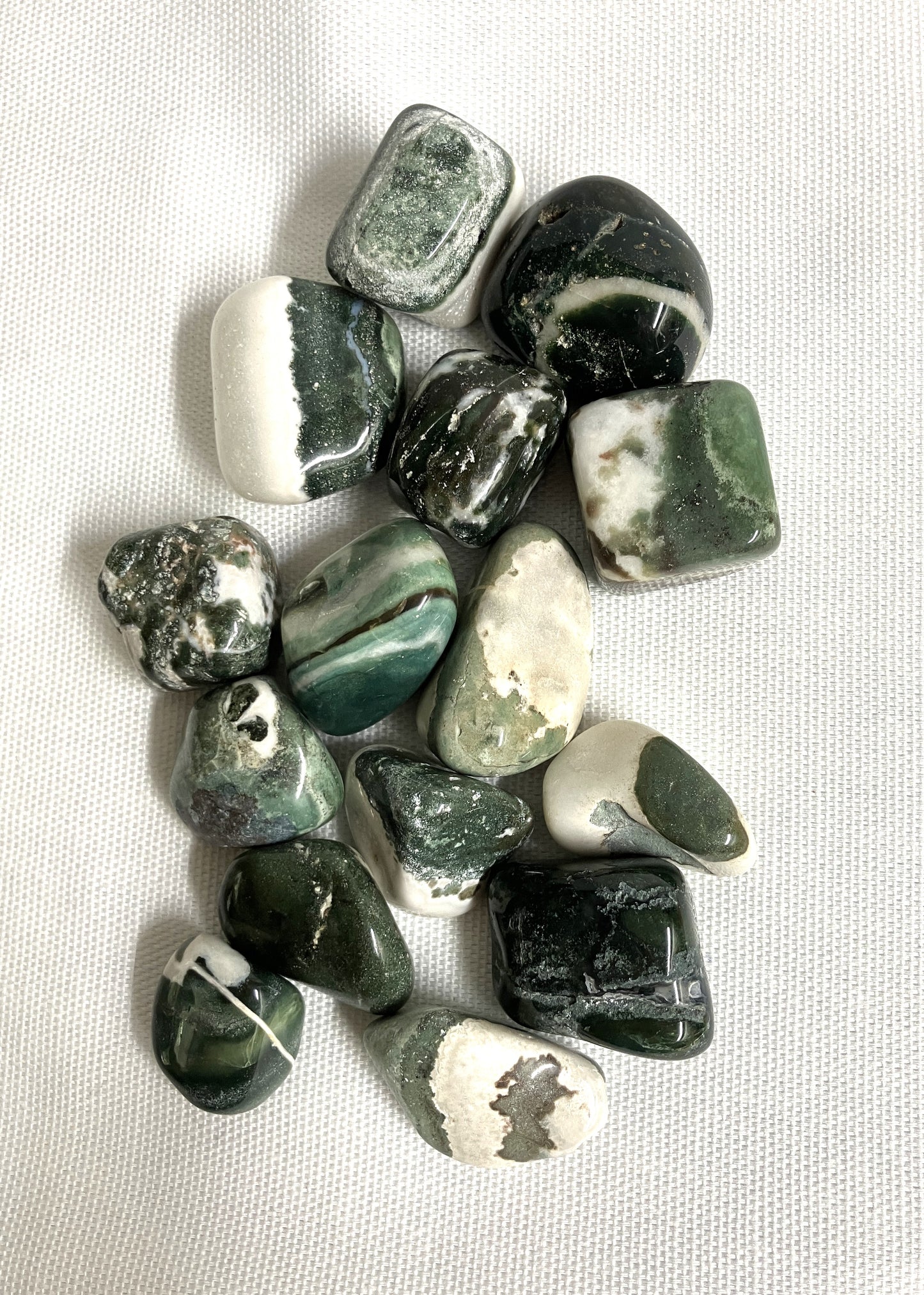 Tumbled Green Sardonyx Crystals on a light fabric background