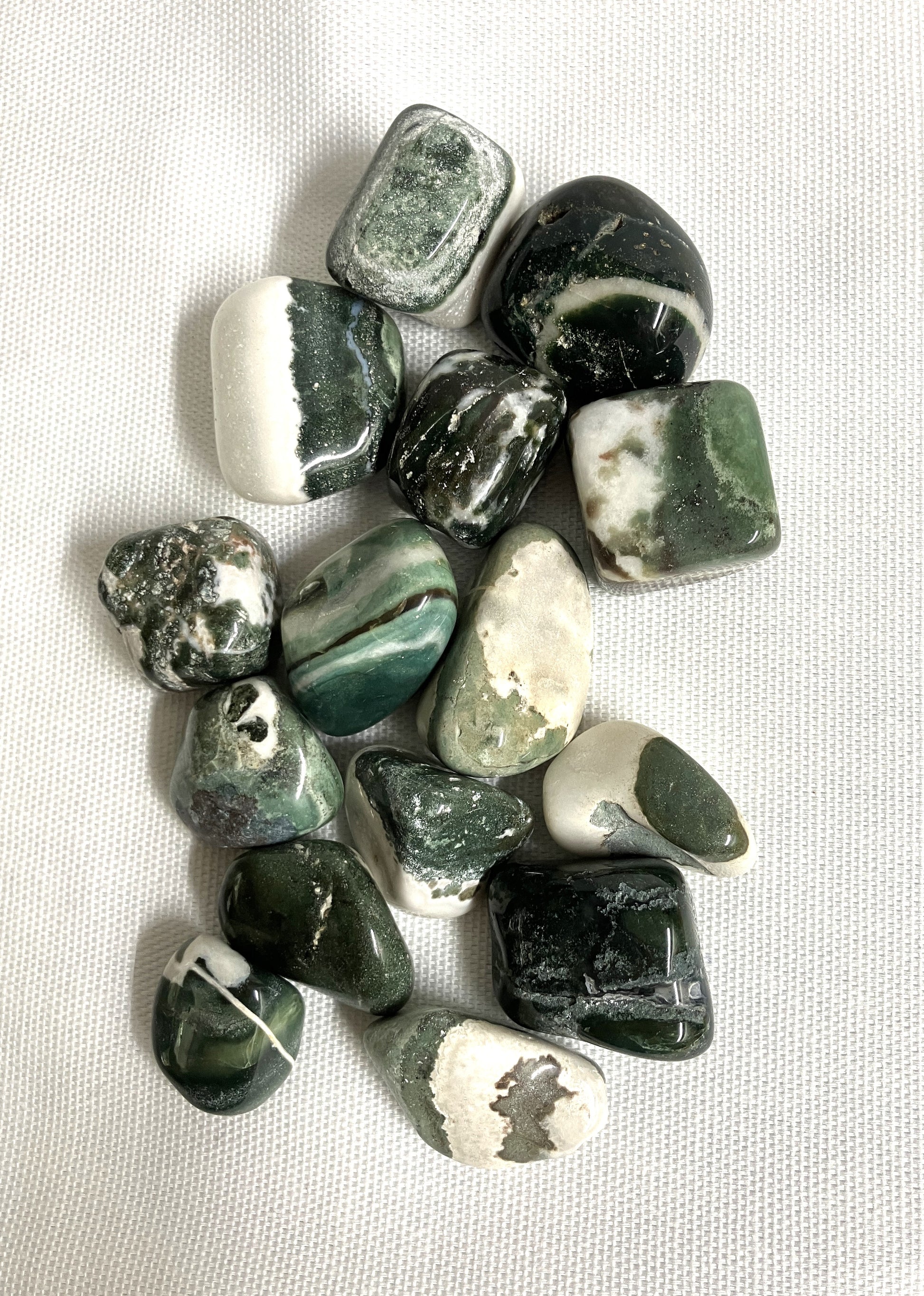 Tumbled Green Sardonyx Crystals on a light fabric background