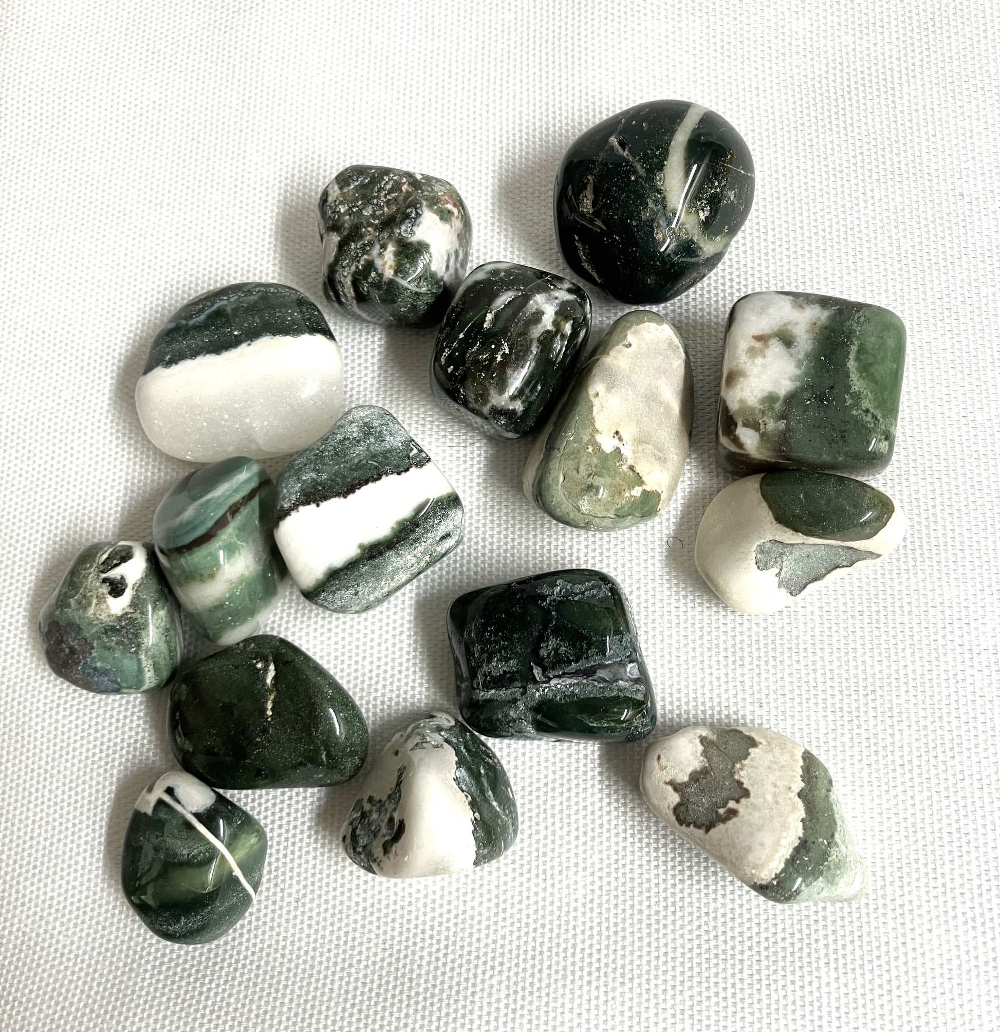 Collection of Green Sardonyx Crystals on a white fabric background