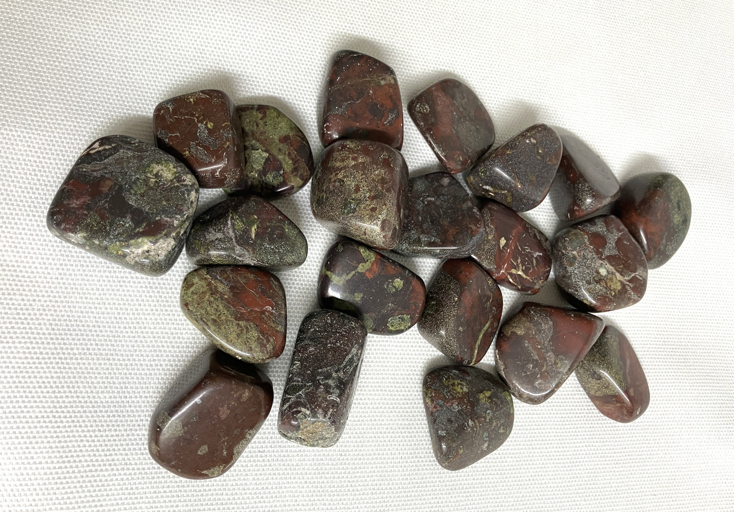 Collection of Tumbled Dragons Blood Crystals on a white fabric background
