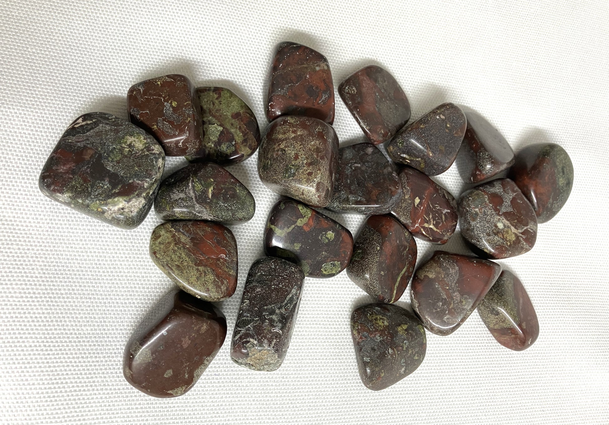 Collection of Tumbled Dragons Blood Crystals on a white fabric background