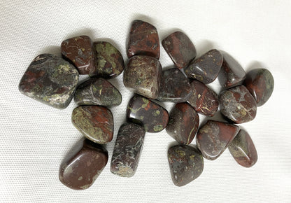Collection of Tumbled Dragons Blood Crystals on a white fabric background