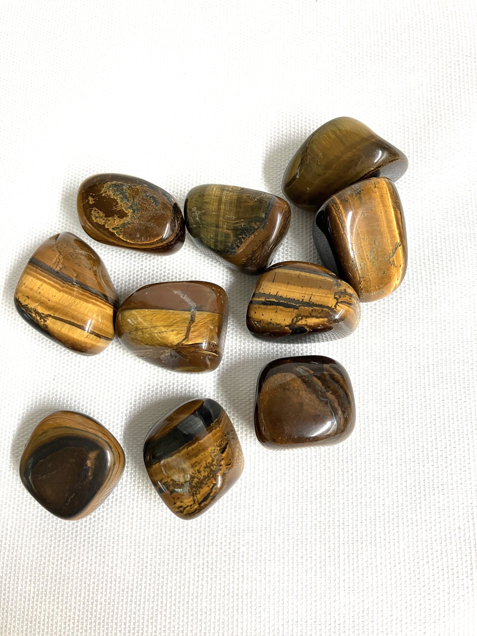Yellow Tiger's Eye Crystals showing the patterns on a white fabric background