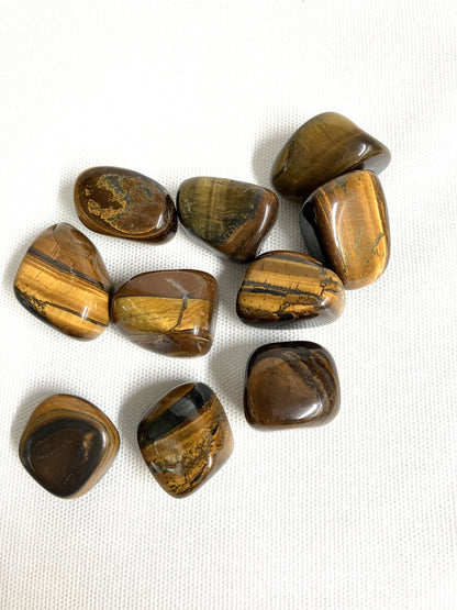 Yellow Tiger's Eye Crystals showing the patterns on a white fabric background