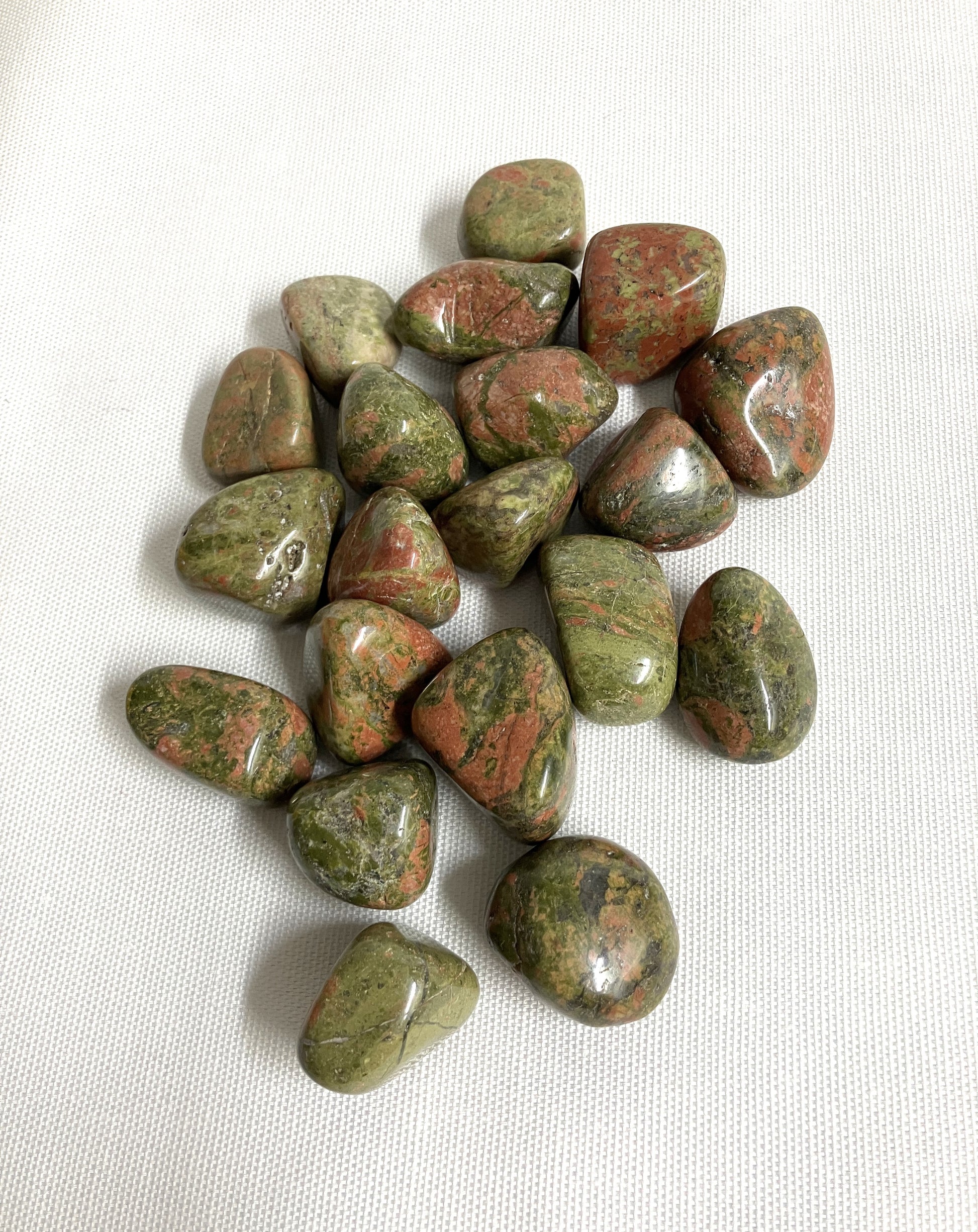 Back view of Unakite Crystal showing patterns and colors on a white fabric background