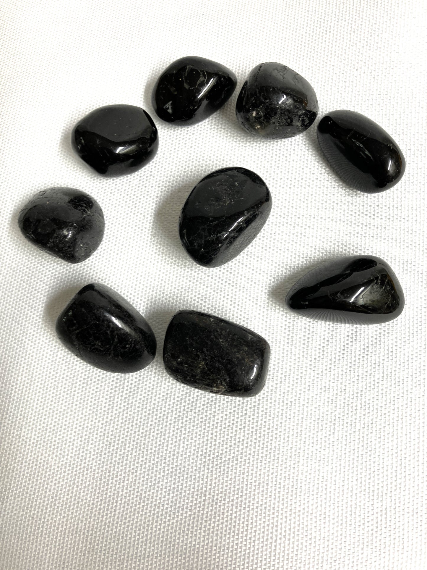Black Tourmaline Crystals arranged on a white fabric background