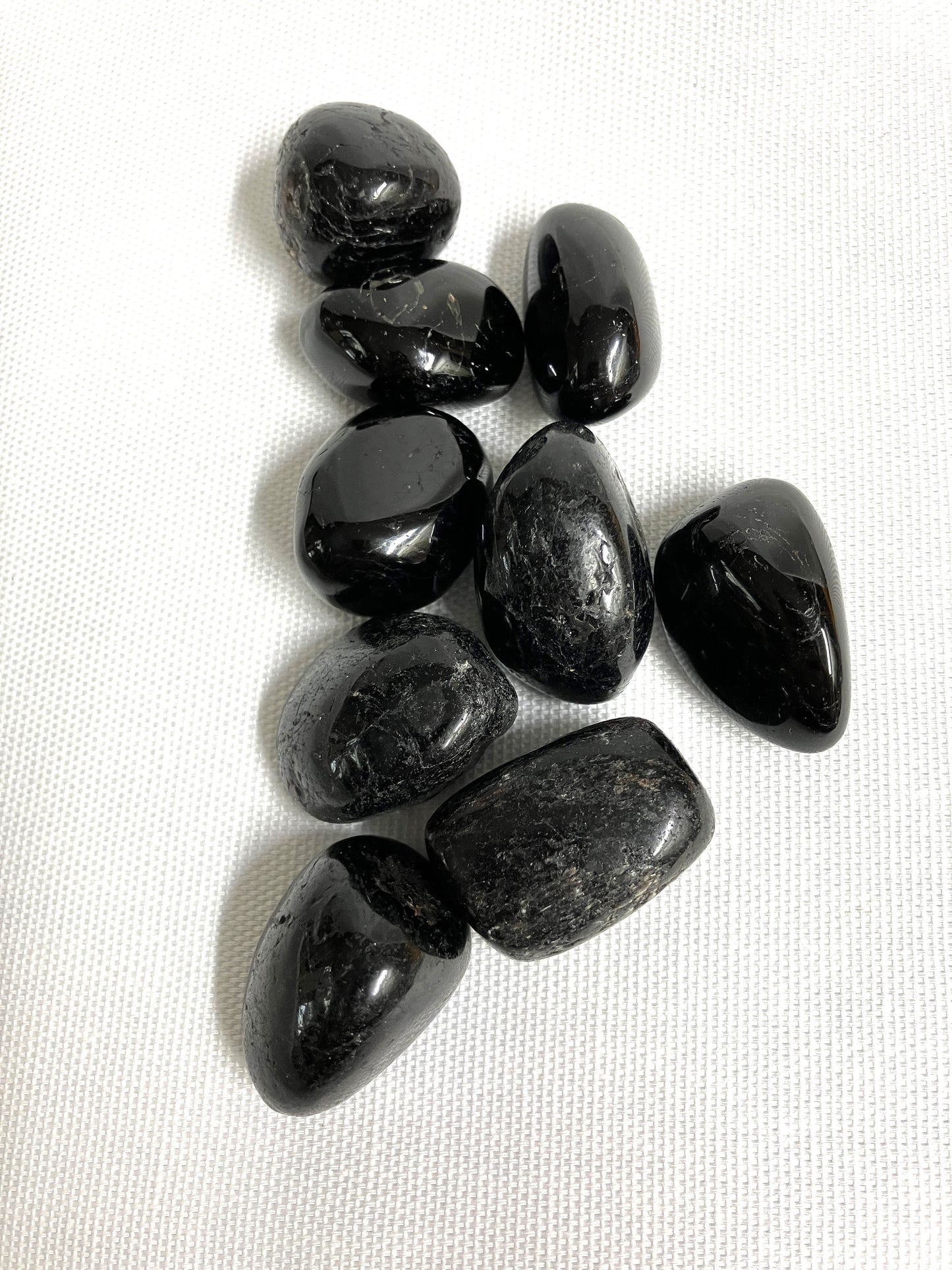 Black Tourmaline Crystals showing the front view on a white fabric background