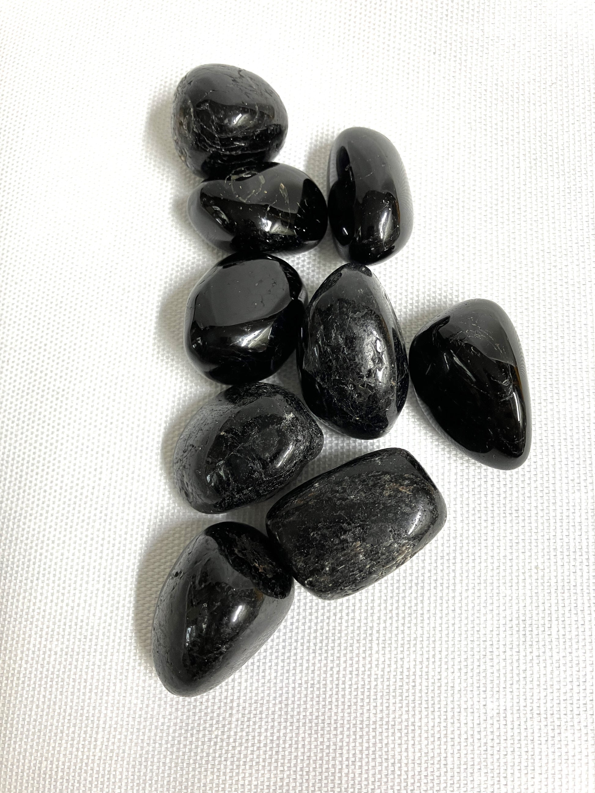 Black Tourmaline Crystals showing the front view on a white fabric background