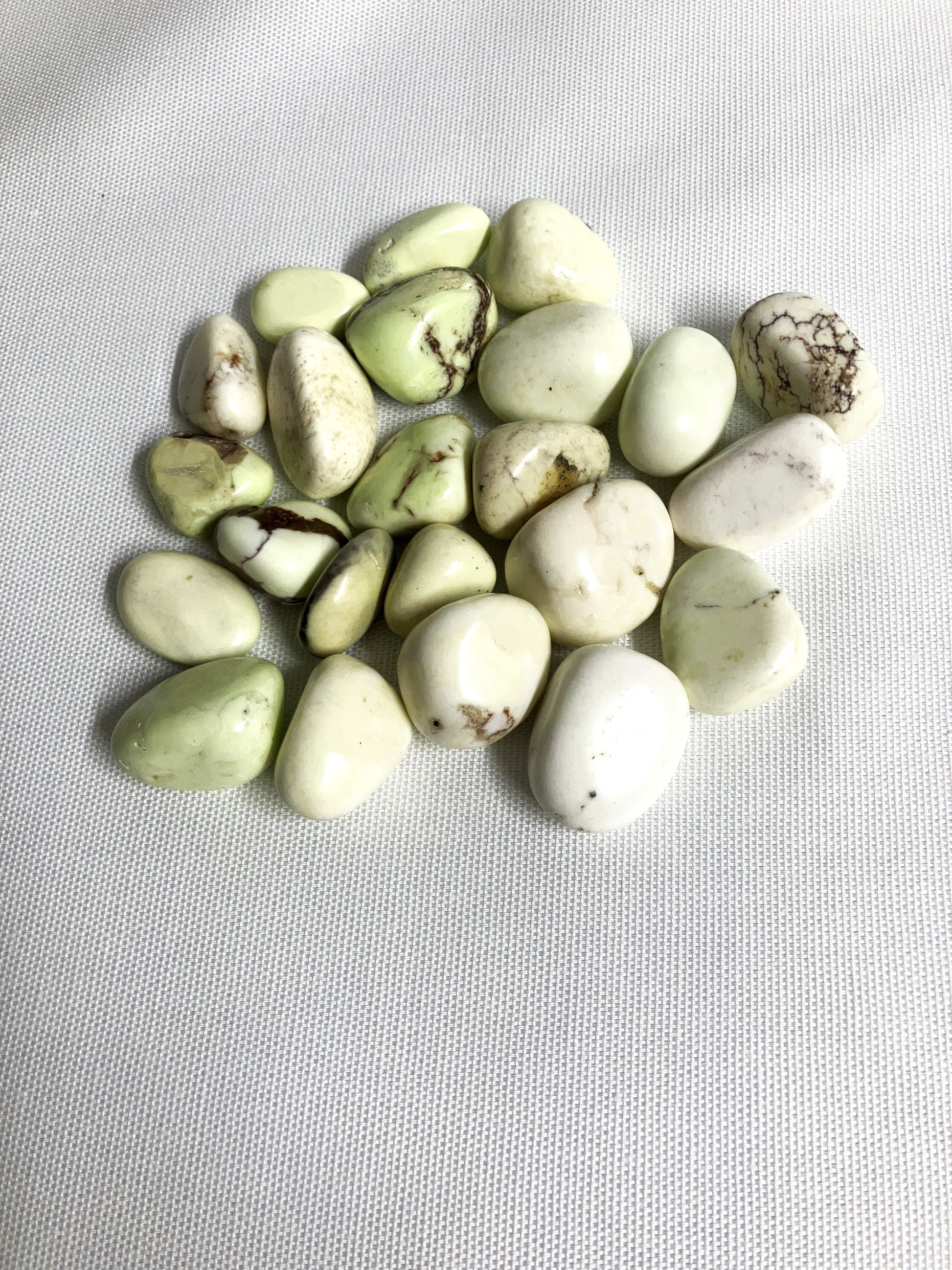 Bottom view of Lemon Chrysoprase Tumbled Crystals on a light gray background