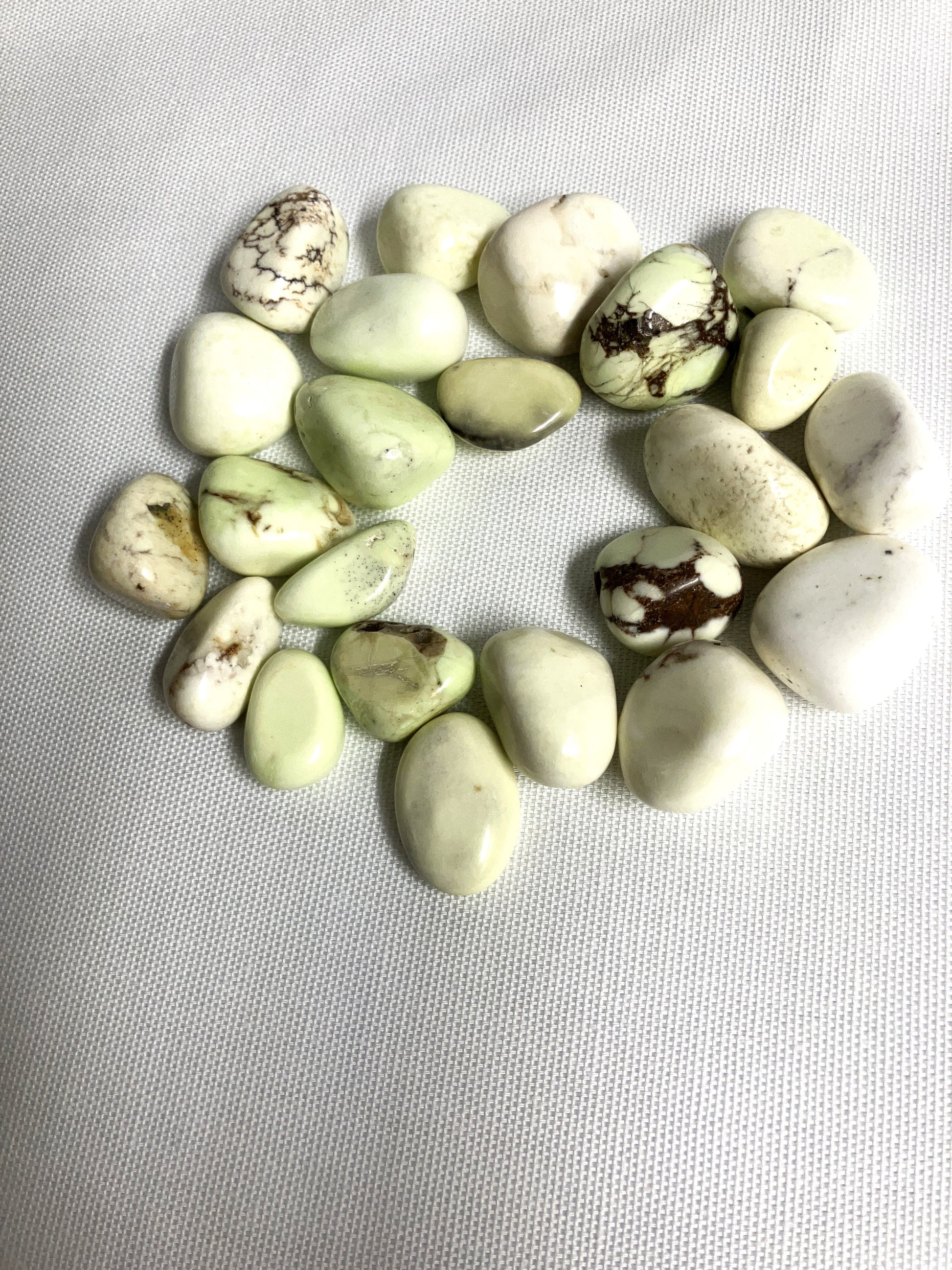 Lemon Chrysoprase Tumbled Crystals in a circular pattern on a light gray background