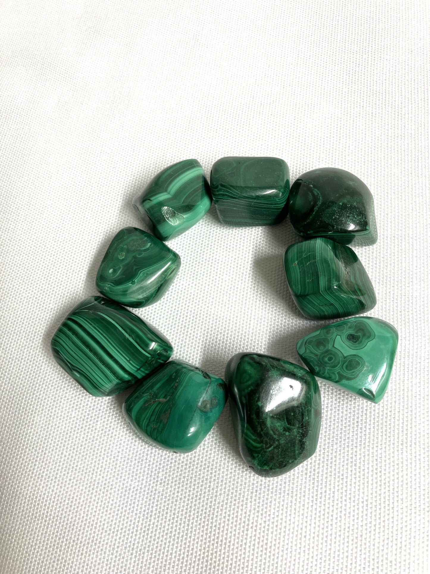 Malachite Crystals showing different patters on a white fabric background