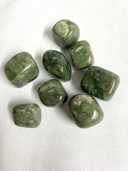 Tumbled Grossularite Crystal aka Green Garnet on a white fabric background