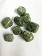 Tumbled Grossularite Crystal aka Green Garnet on a white fabric background