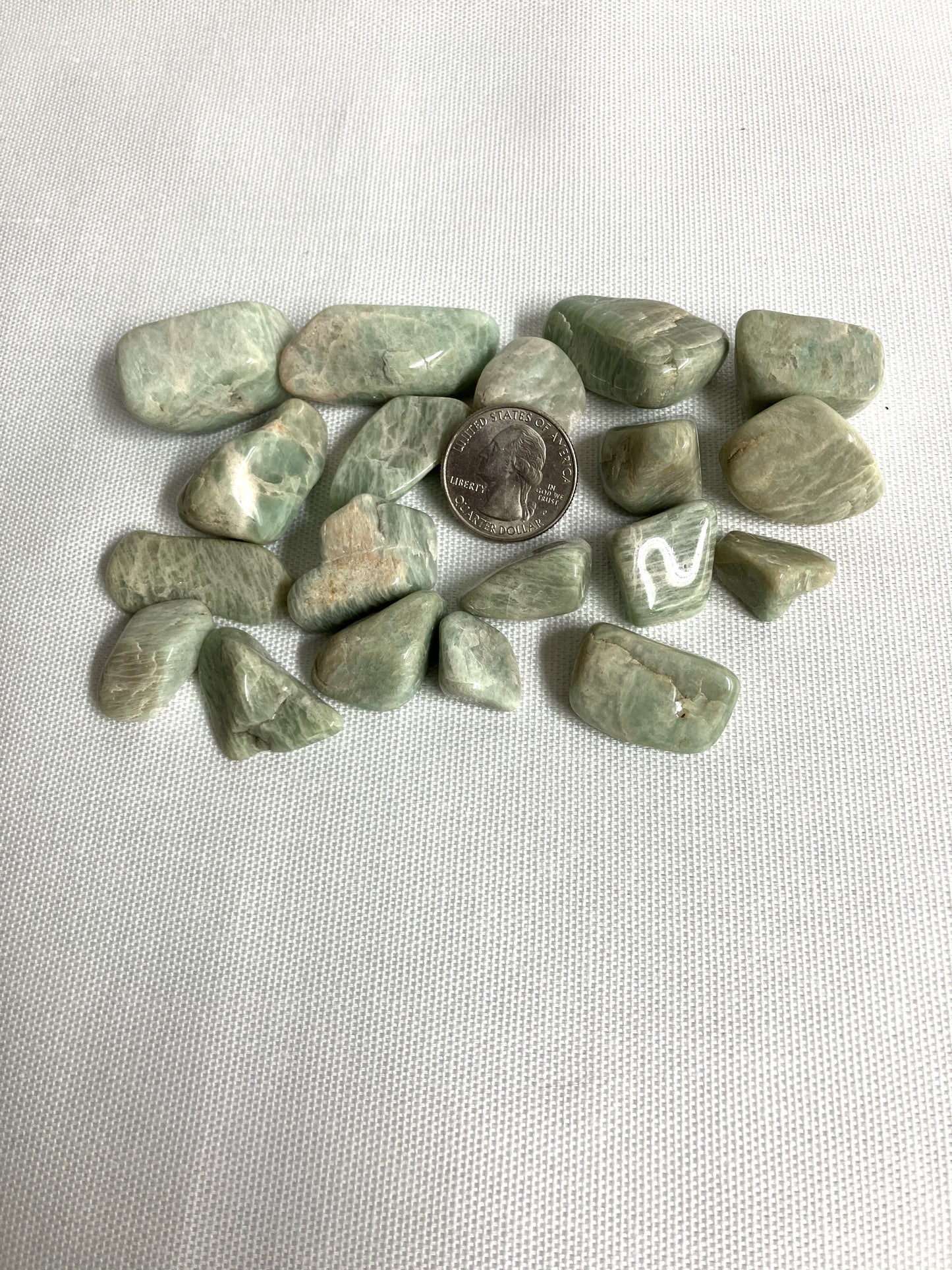 Amazonite Crystals on a white fabric background with a quarter for scale