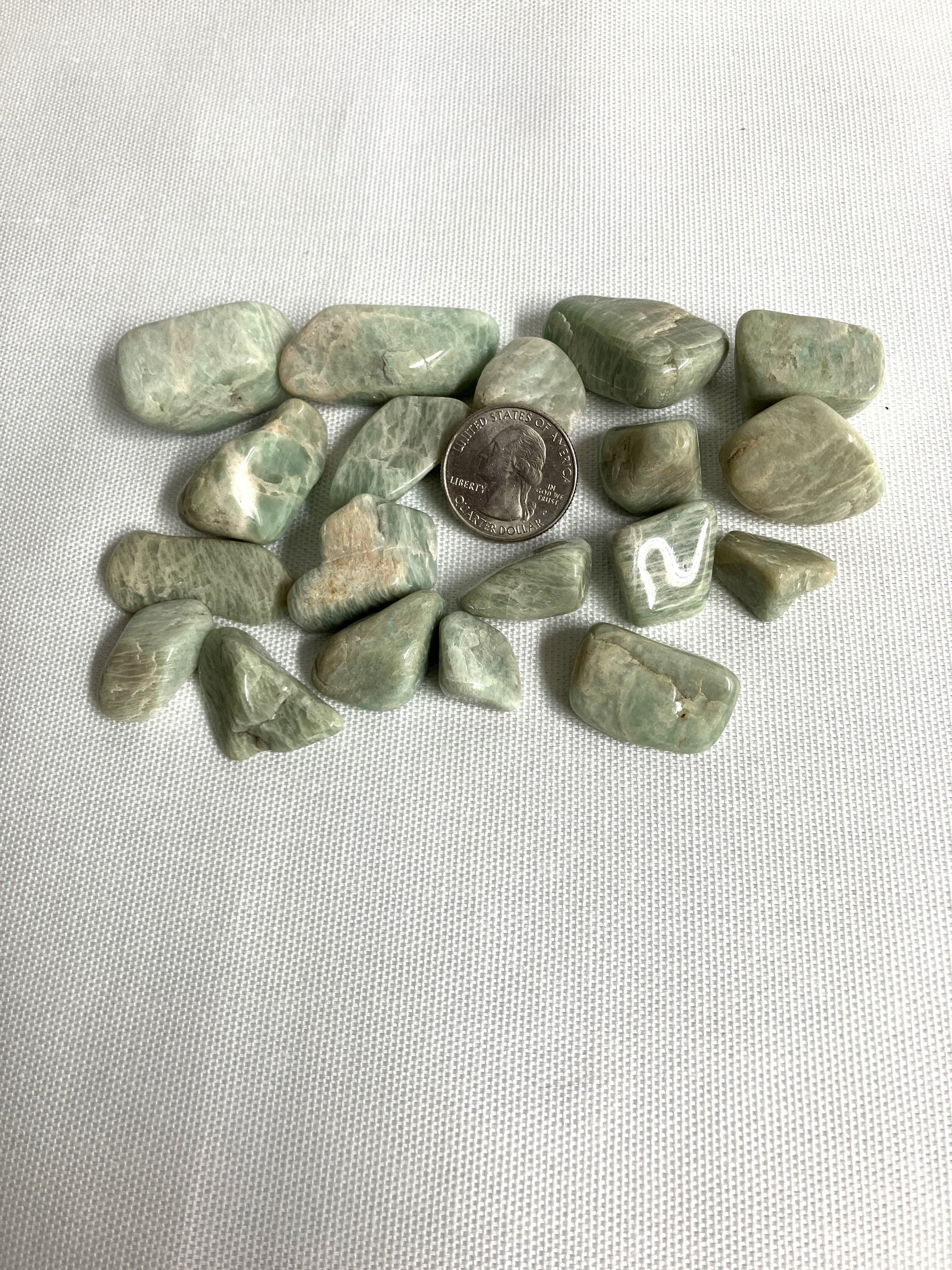 Amazonite Crystals on a white fabric background with a quarter for scale